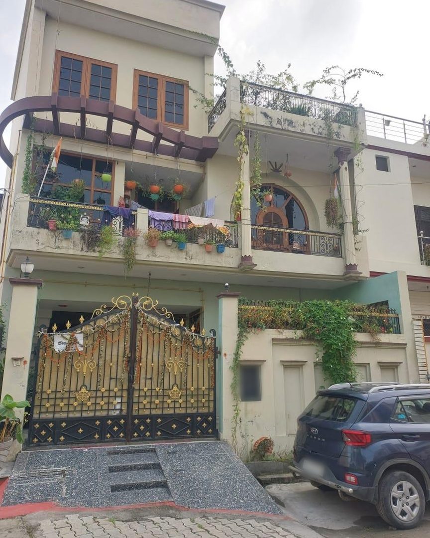 The house before the redesign — front elevation with an ornate gate, a curved pergola and open balconies